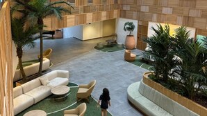 Un hall d’entrée spacieux avec un plafond haut, un espace salon central et un escalier menant à un niveau supérieur.