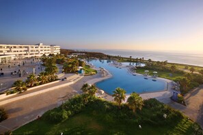 A resort with a large pool, palm trees, and a view of the ocean. - Lixus Beach Resort – All Inclusive (Larache)