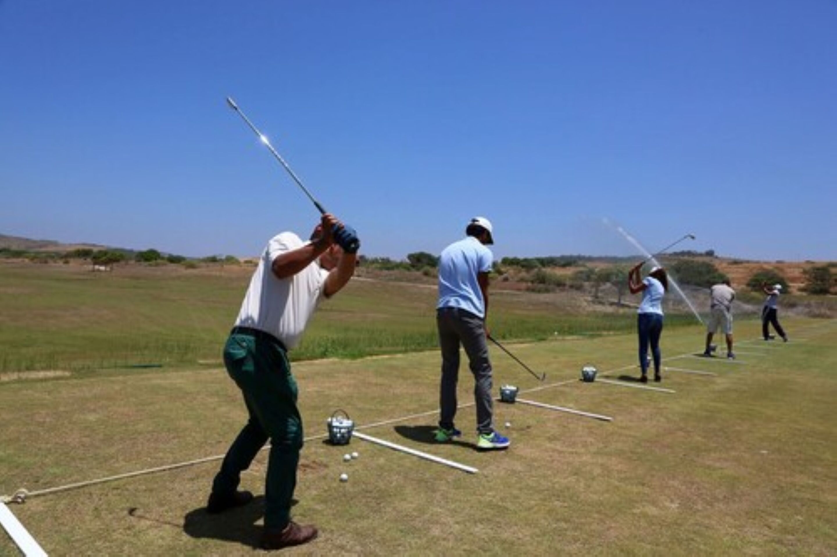 A golf course with players practicing their swings.
