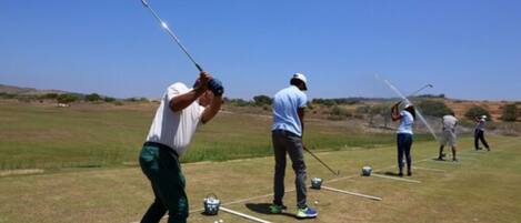 A golf course with players practicing their swings.