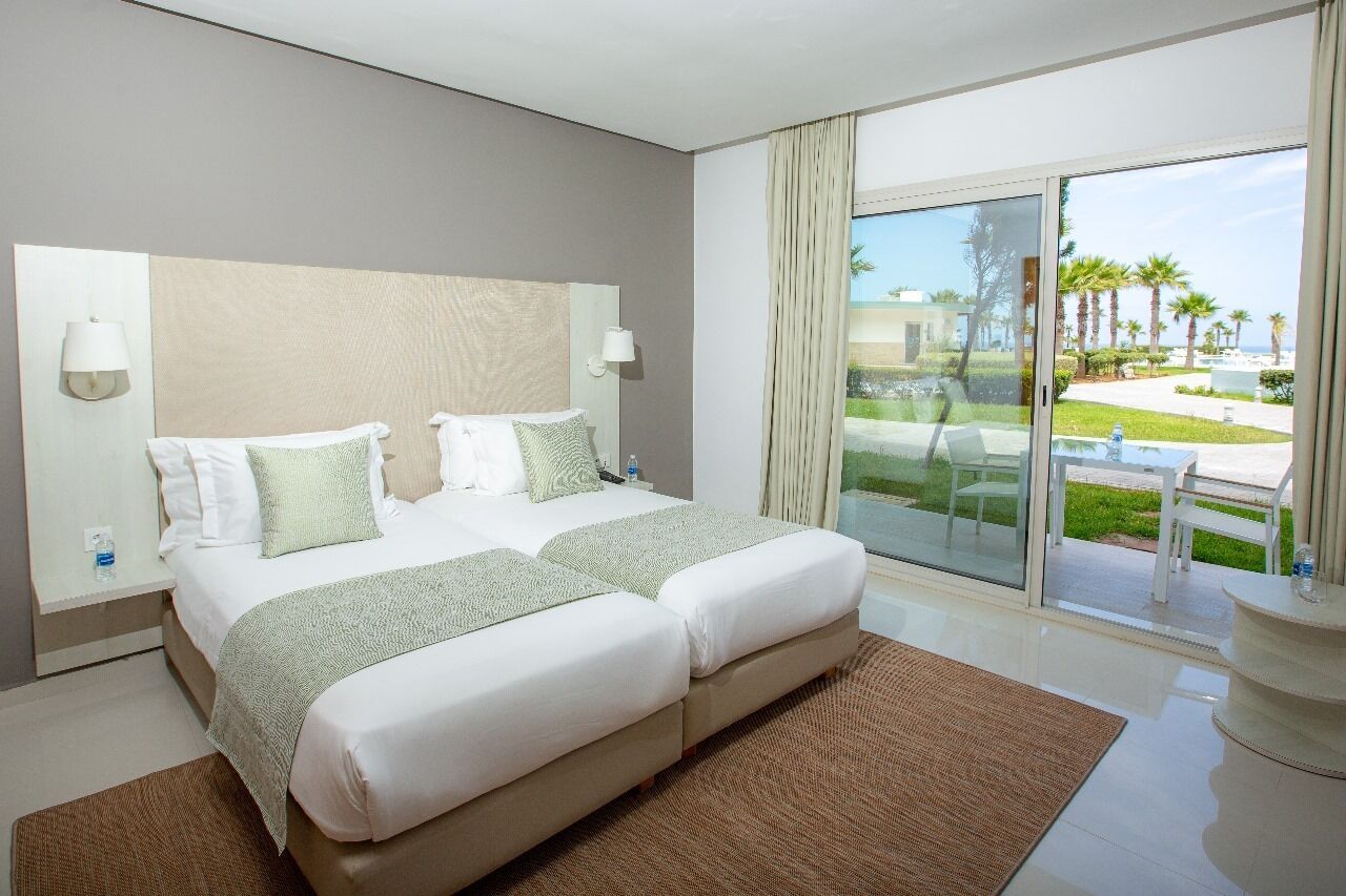 A hotel room with a large bed, a view of the outdoors, and a balcony.