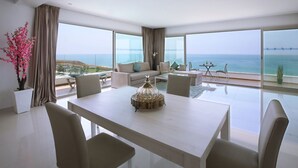 Un salon moderne doté d’une grande table à manger, de canapés et offrant une vue sur l’océan.
