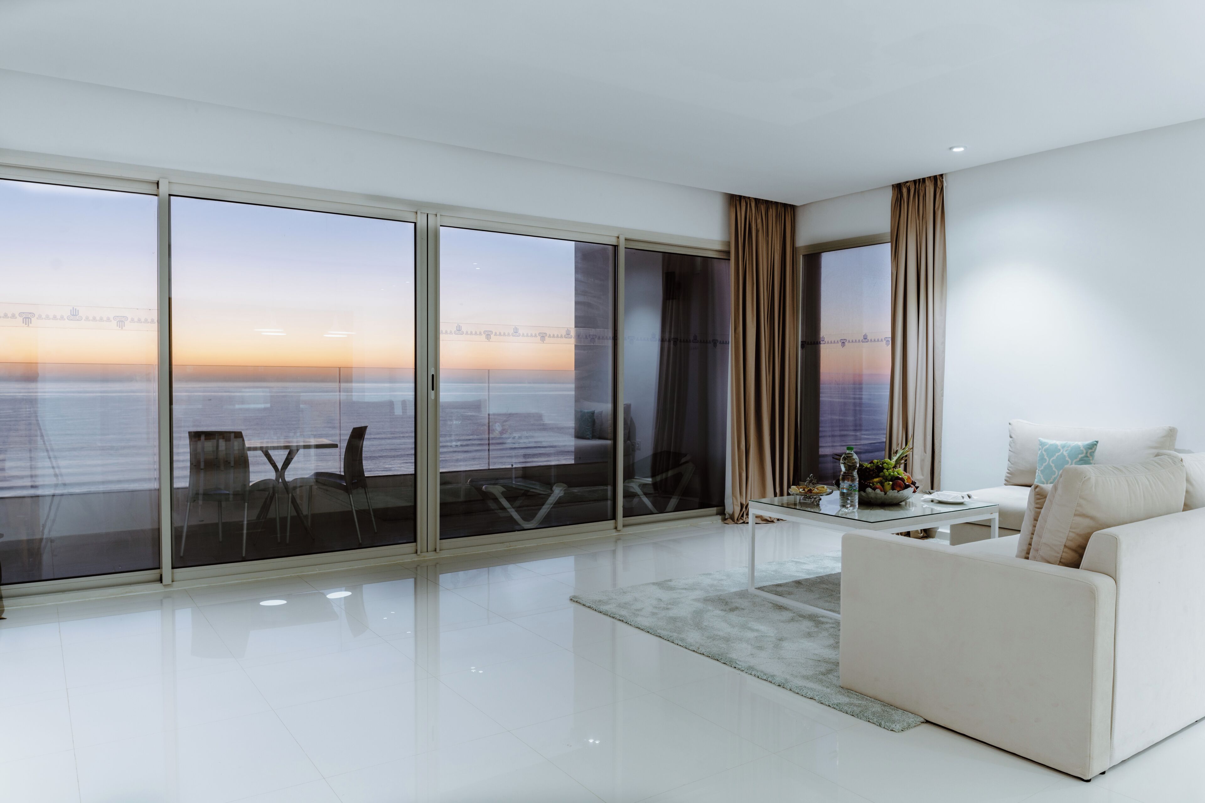 Un moderno salón con un amplio ventanal, un sofá, una mesa de centro y vistas panorámicas de la ciudad.