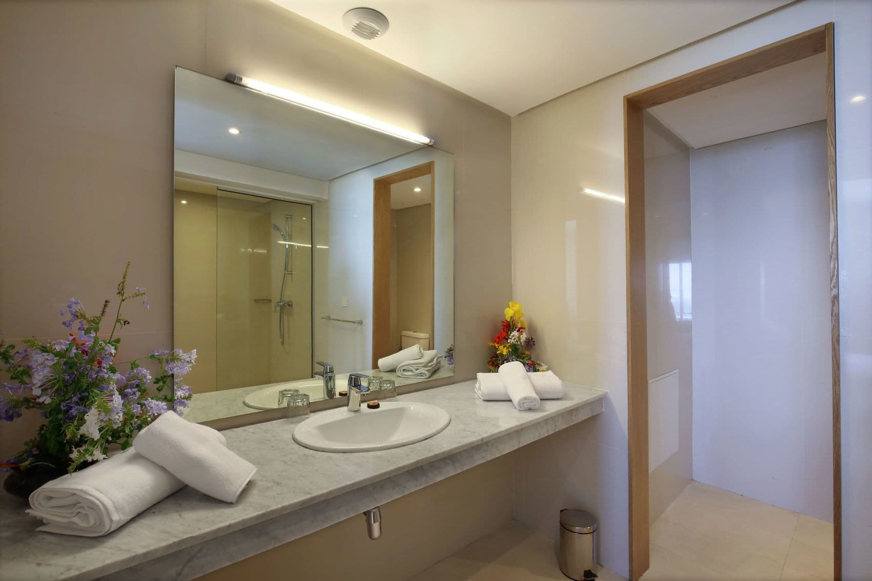 Un baño moderno con dos lavamanos, un espejo grande y una ducha.
