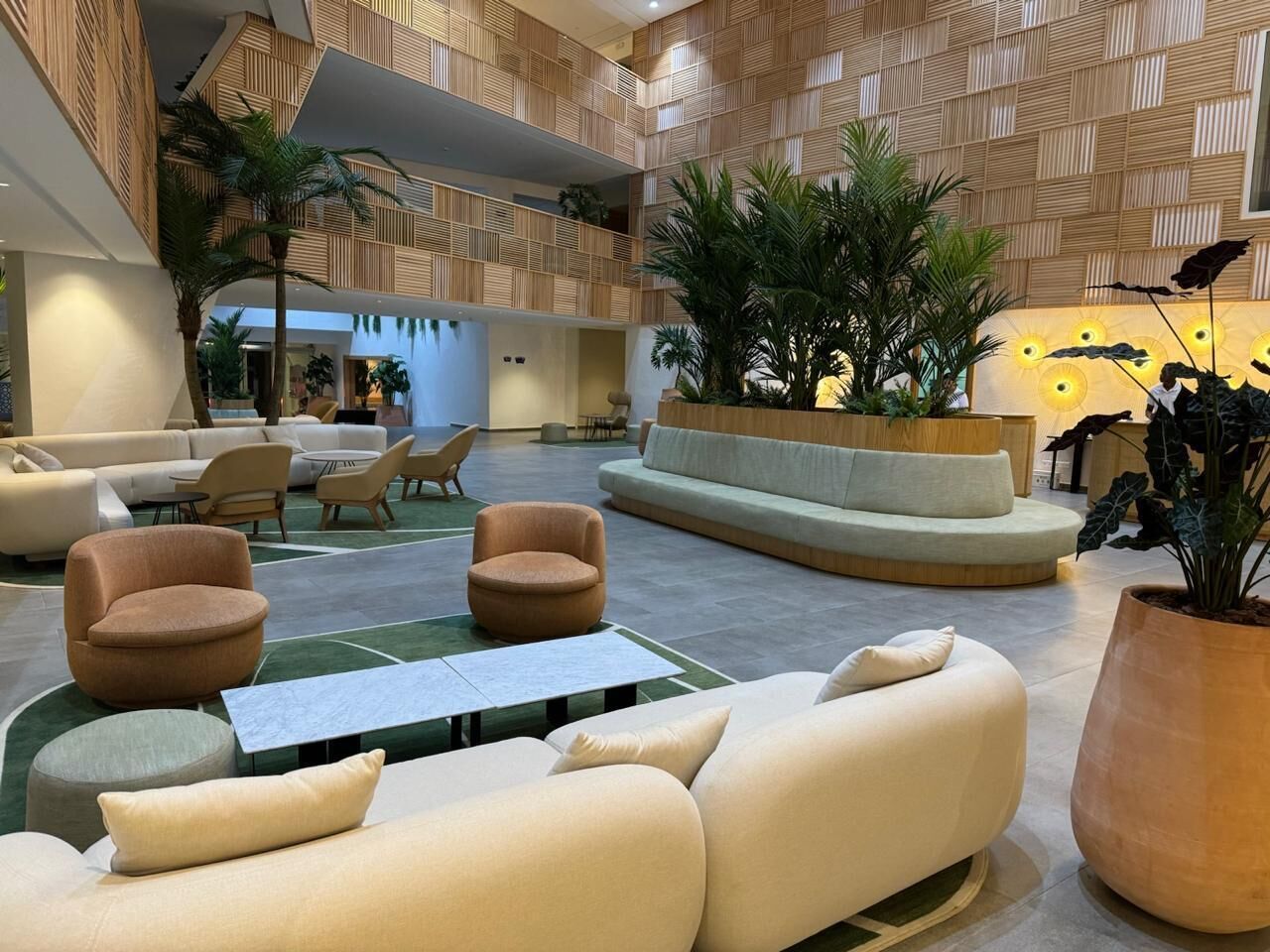A spacious lobby with a high ceiling, modern furniture, and indoor plants.