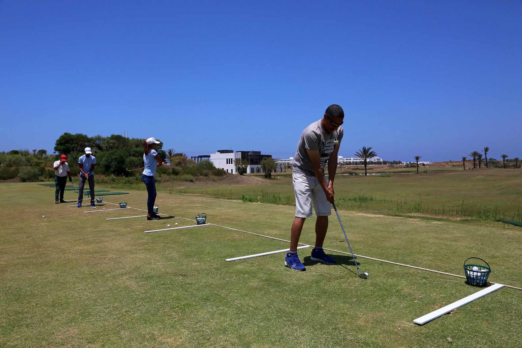 A golf course with players practicing their swings.