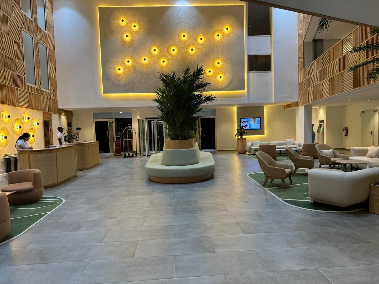 En rummelig lobby med en central plante, siddeområder og en receptionsdisk.