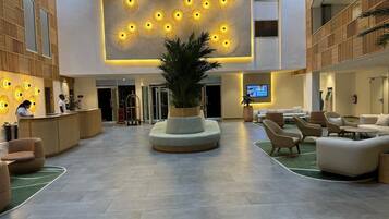 En rummelig lobby med en central plante, siddeområder og en receptionsdisk.