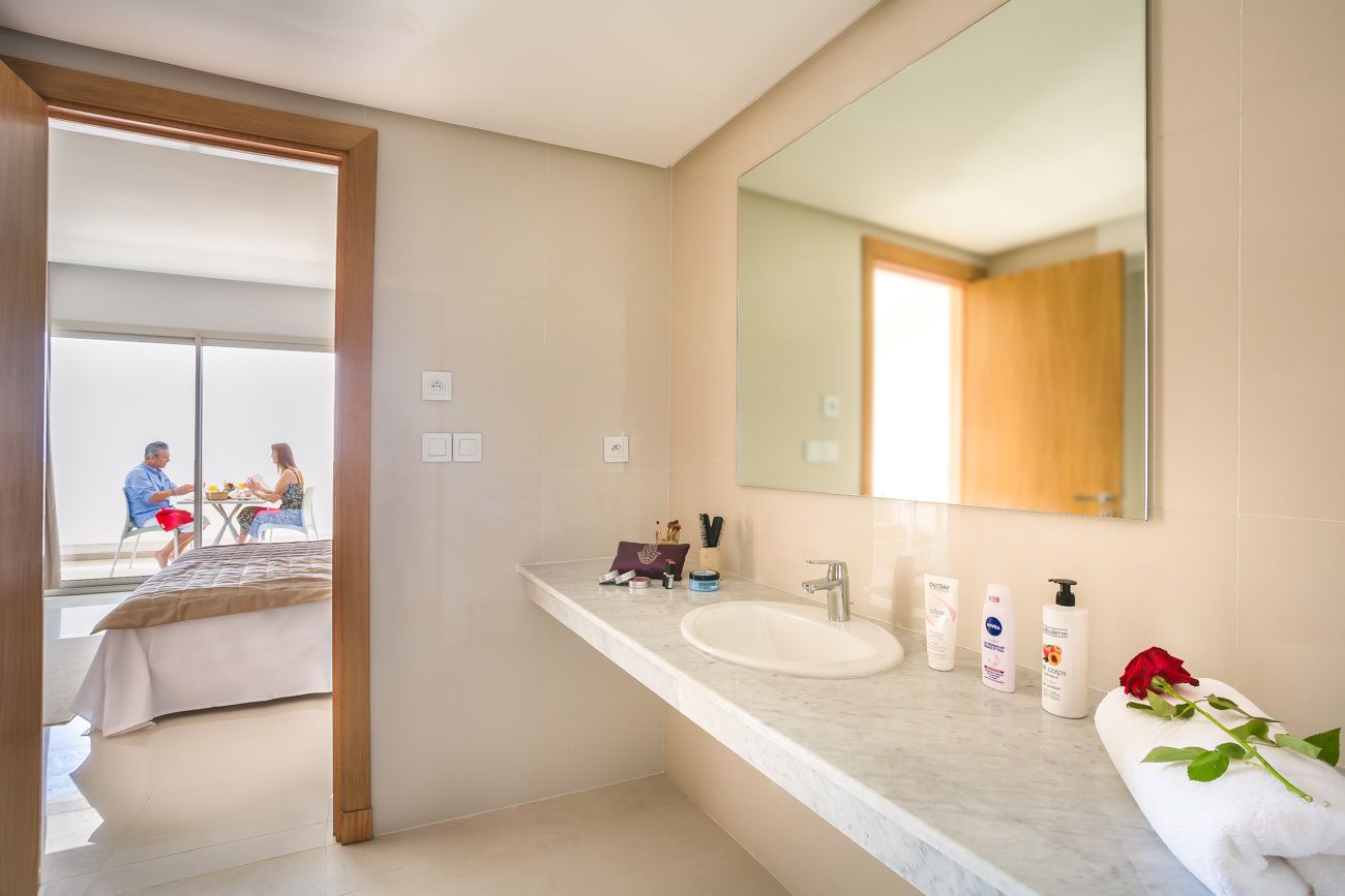 Une salle de bain moderne avec un grand miroir, un lavabo et des articles de toilette posés sur le comptoir.