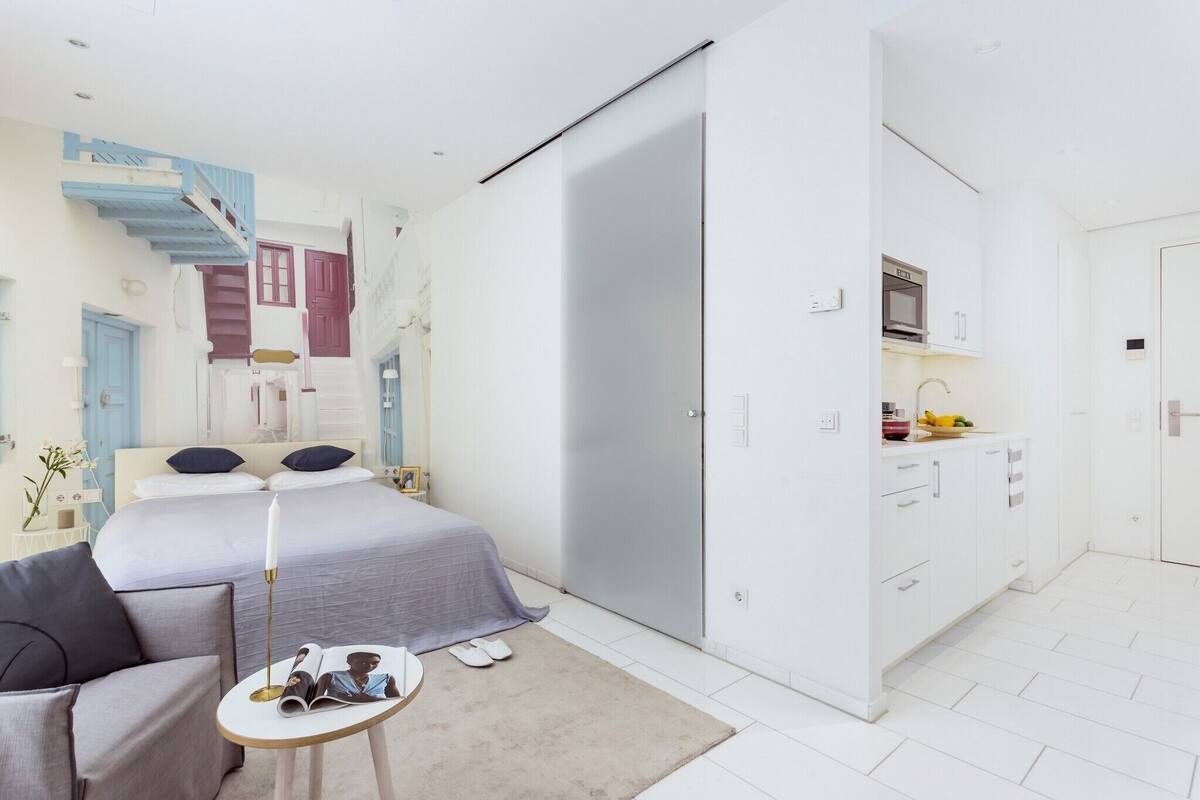 Un dormitorio moderno con cama, mesita de noche y una pequeña zona de estar.