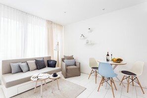 A modern living room with a sofa, a small table, two chairs, a side table, and a dining area with a table and chairs. - Skyreach Bizzstay - Wohnen Am Main (Frankfurt)