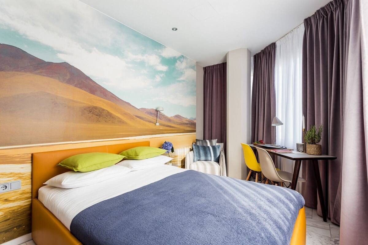Una habitación de hotel con una cama, un escritorio y una silla.