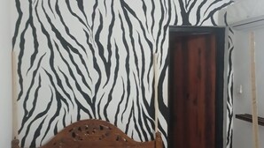 Un dormitorio con pared a rayas de cebra, estructura de cama de madera y colcha a rayas azules.