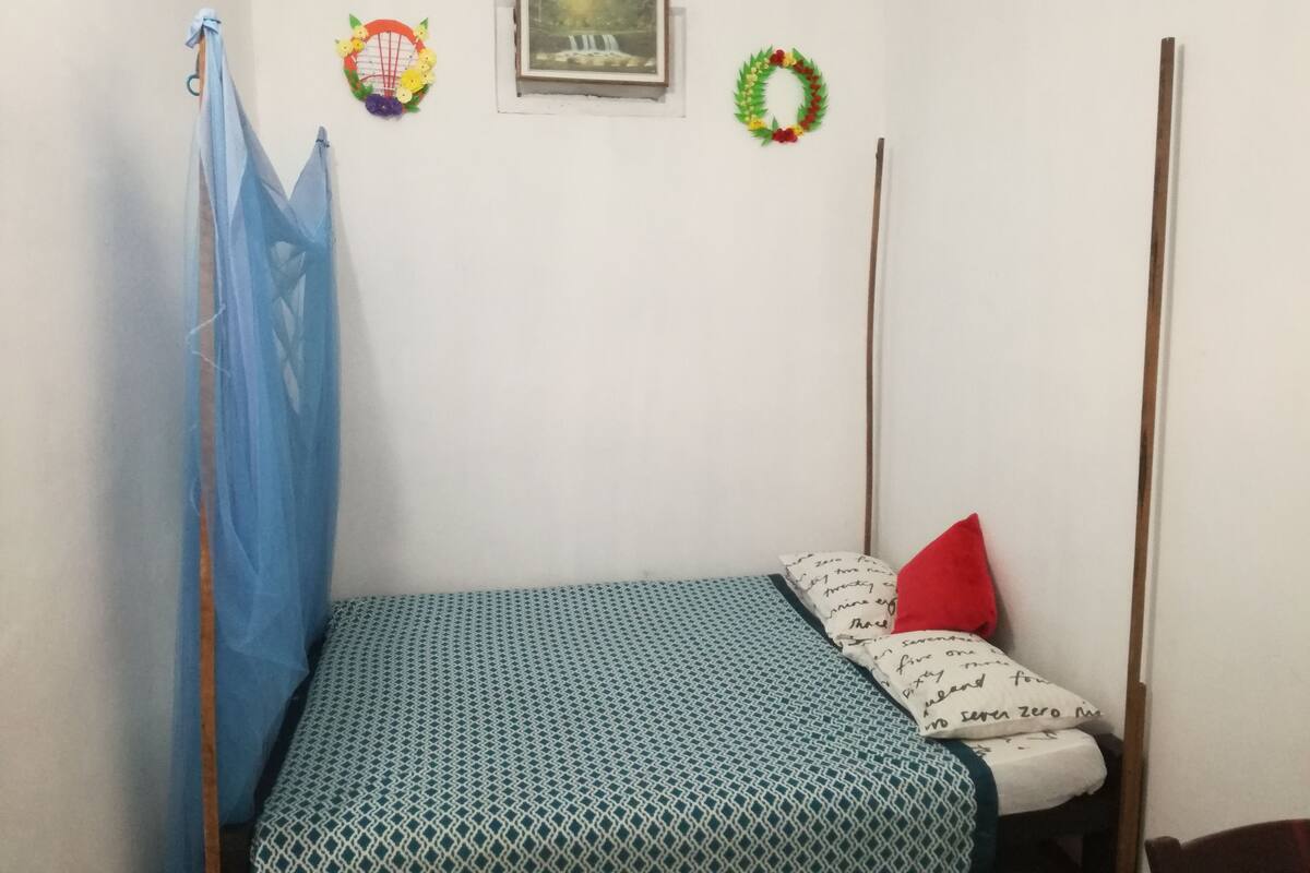 A small room with a bed, a window, and a picture on the wall.