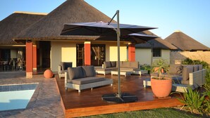 A resort with thatched-roof buildings, outdoor seating, and a swimming pool. - ParkView Lodge (Colchester)