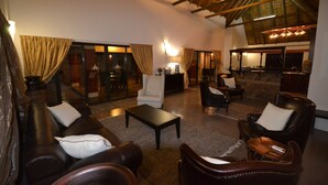 A spacious living area with leather sofas, a coffee table, and a fireplace. There are curtains, a television, and a kitchen area visible. - ParkView Lodge (Colchester)