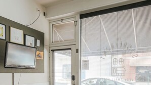 A modern living room with a large window, a flat-screen TV mounted on the wall, a cozy sofa, a small table, and a decorative rug. - The Storefront (Staunton)