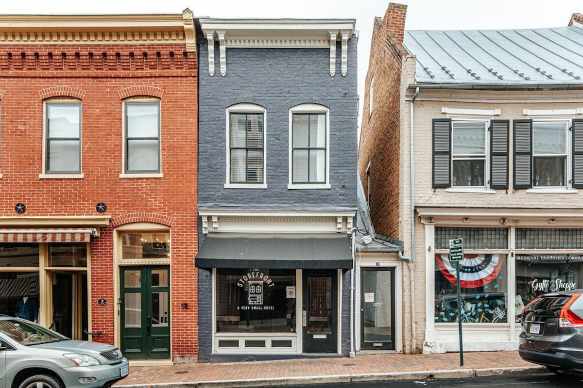 A row of three-story buildings with distinct architectural styles, including a brick facade, a gray stone building, and a white building with black shutters.