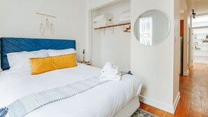 A bedroom with a large bed, a wardrobe, a mirror, and a hanging light fixture. - The Storefront (Staunton)