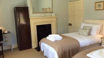 A hotel room with a bed, a dresser, a mirror, a fireplace, and a door.