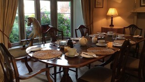 A dining room with a round table set for a meal, surrounded by wooden chairs.