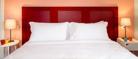 Una habitación de hotel con una cama grande, dos mesitas de noche y un cabecero rojo.