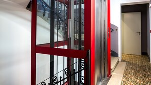 A staircase with a red frame and black balustrade, leading to a room with a patterned floor. - Almarossa (Bologna)