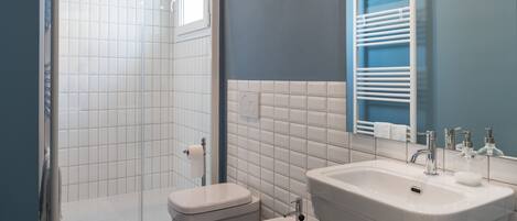 Un baño moderno con ducha, dos inodoros, un lavabo y un espejo.