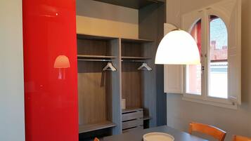 A modern room with a dining table, chairs, a hanging light fixture, and a window with a view.