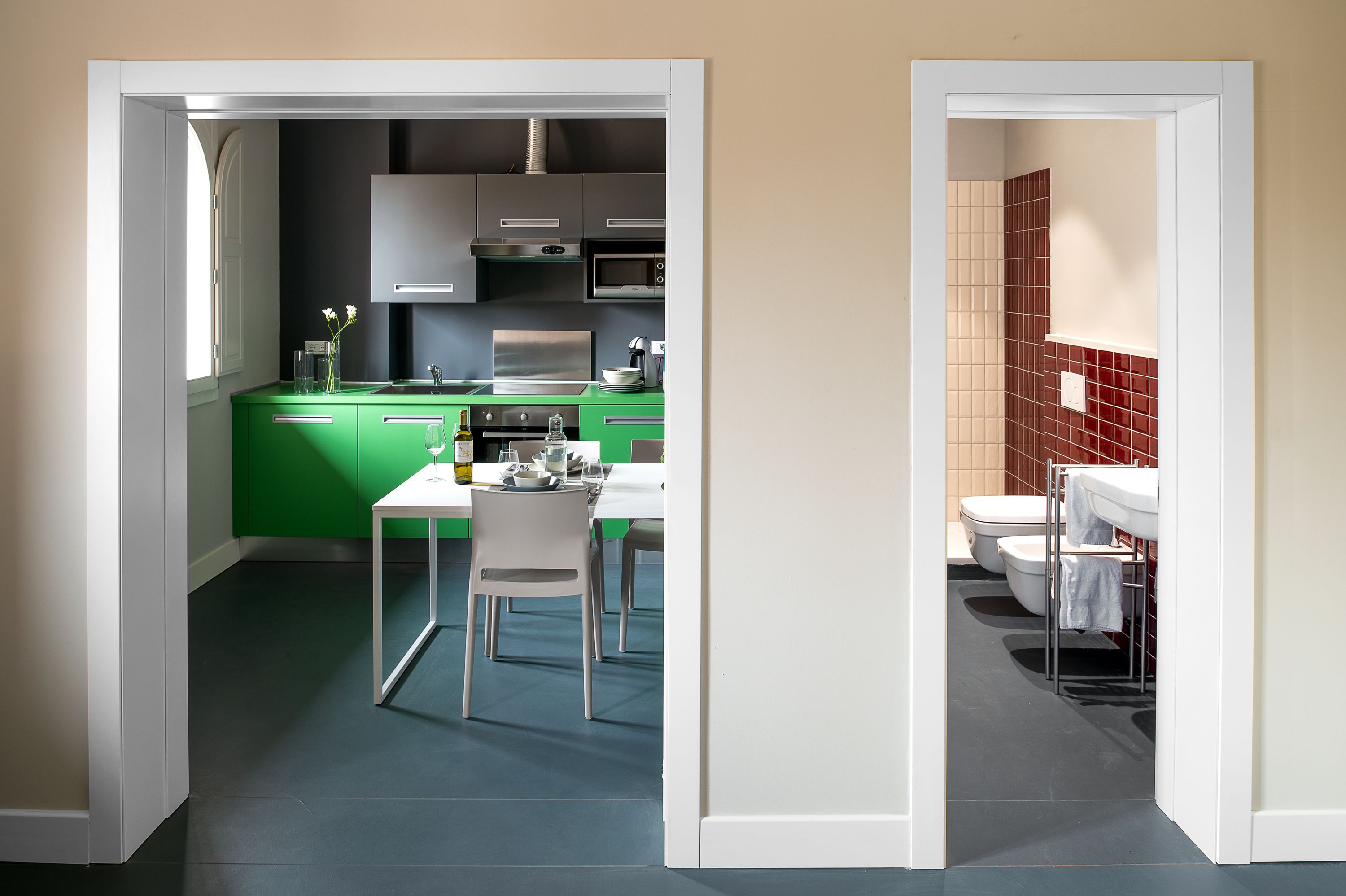 Eine moderne Küche mit grünen Schränken und einem Essbereich mit weißem Tisch und Stühlen.