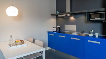 A modern kitchen with blue cabinets, a white table, and a hanging light fixture.