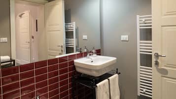 A bathroom with a white sink, red-tiled walls, and a towel rack.