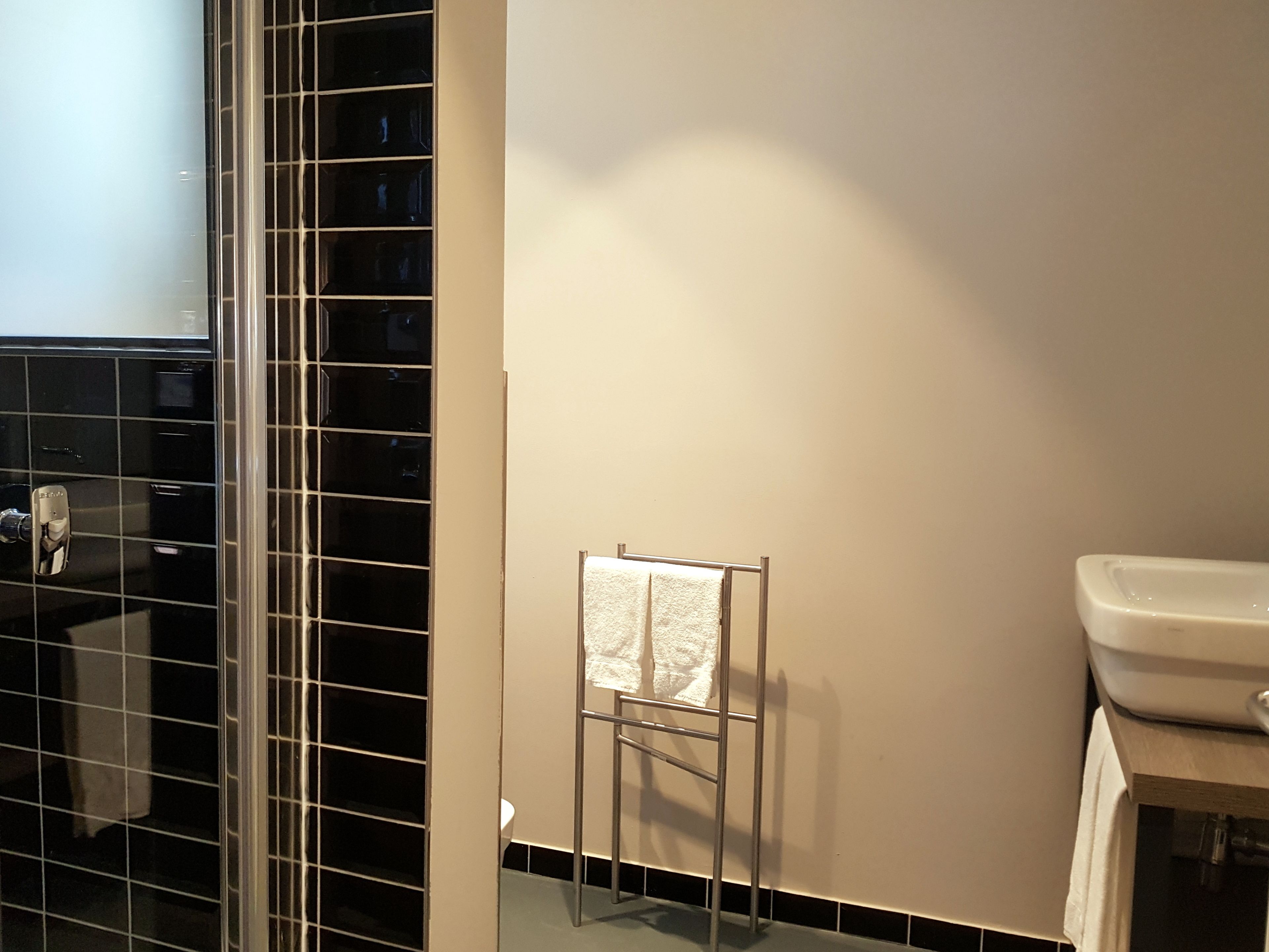 Une salle de bain avec une douche à parois de verre, un porte-serviettes blanc et un lavabo blanc.