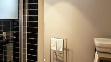A bathroom with a glass shower enclosure, a white towel rack, and a white sink.