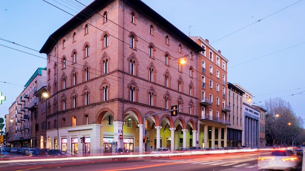 A large, red-brick building with multiple floors and arched windows. - Almarossa (Bologna)