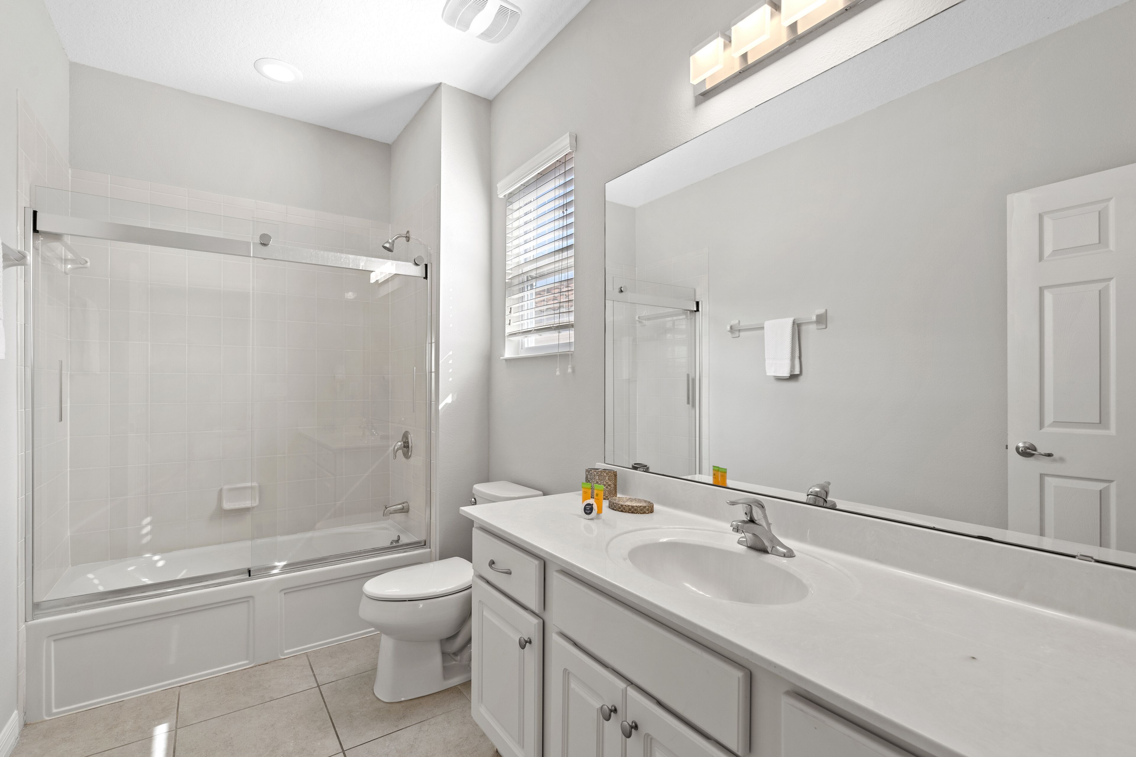 A modern bathroom with a glass-enclosed shower, a white toilet, a large mirror, and a white sink.