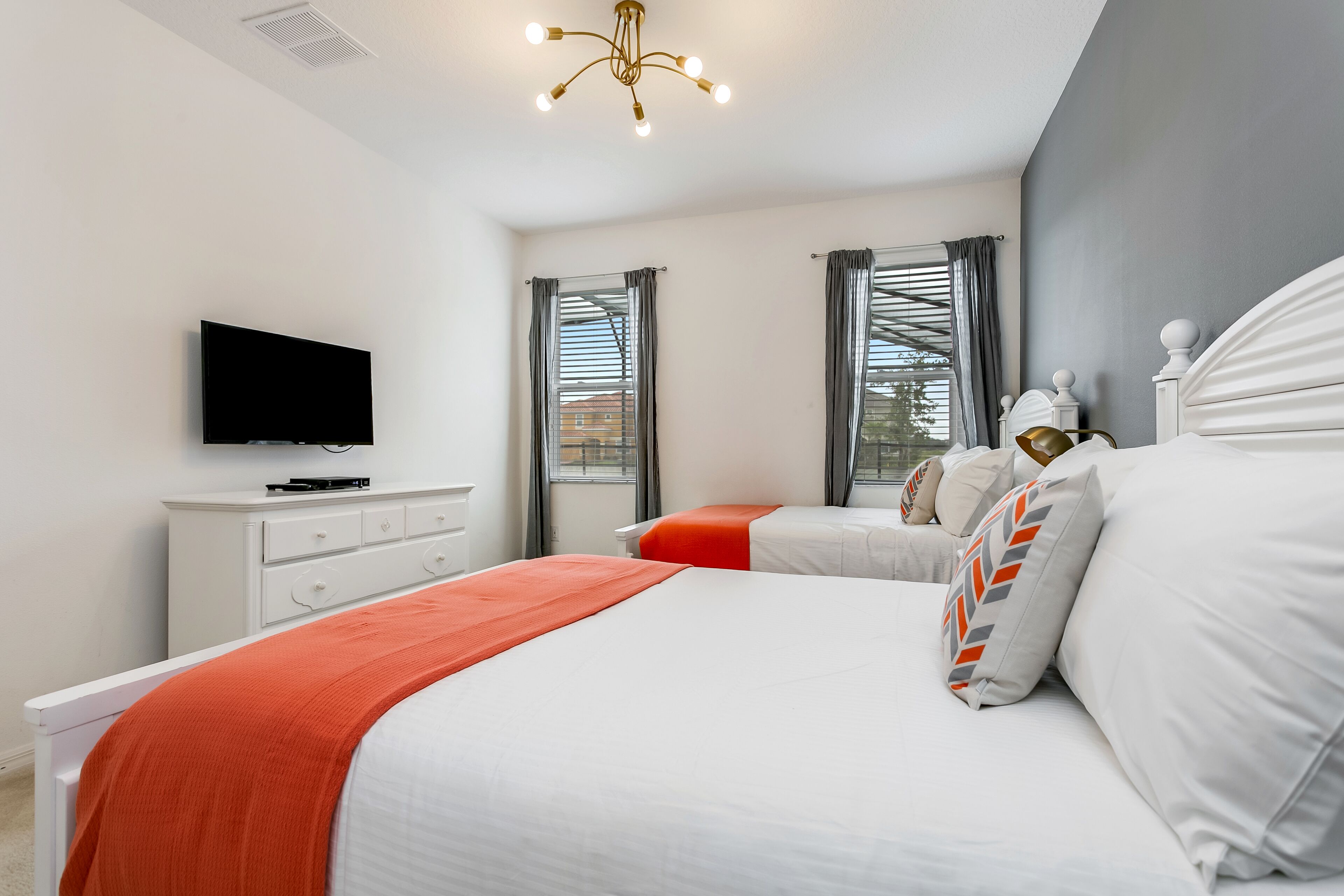 A hotel room with two beds, a TV, and a window with curtains.