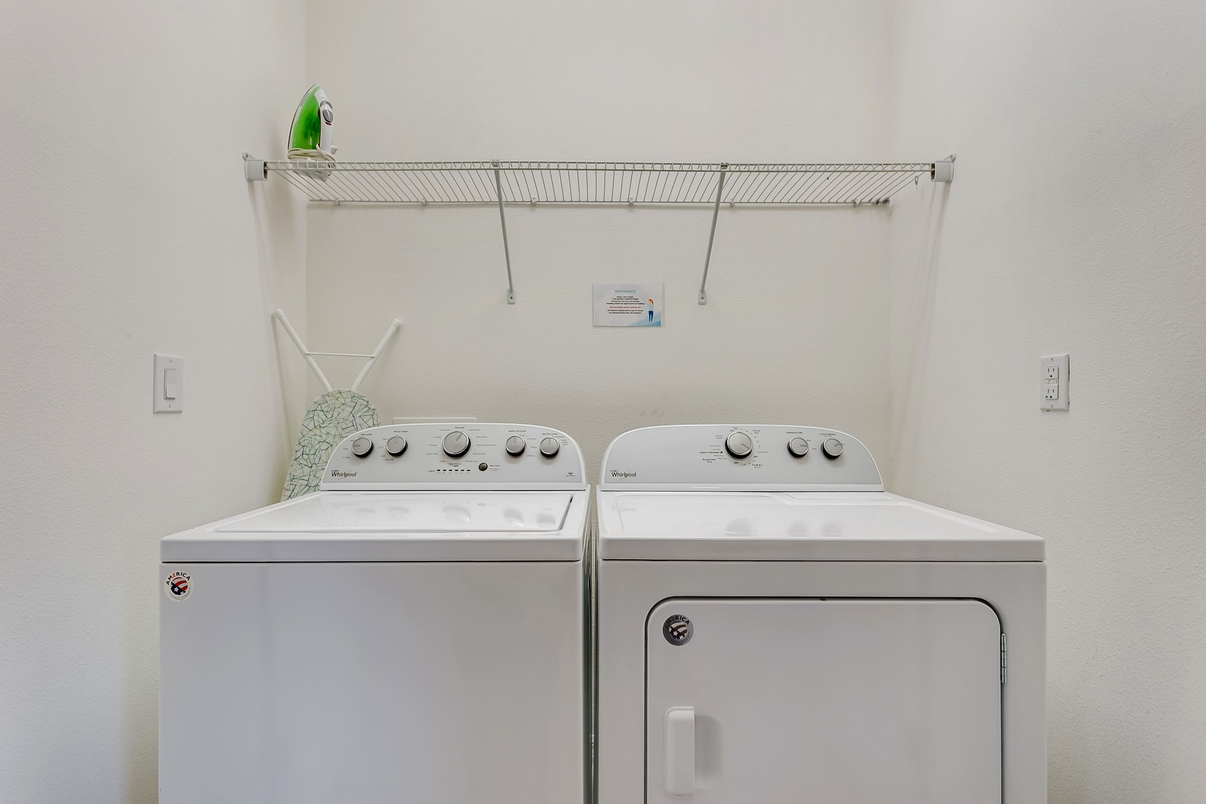 A laundry area with two white Whirlpool washers and a drying rack.