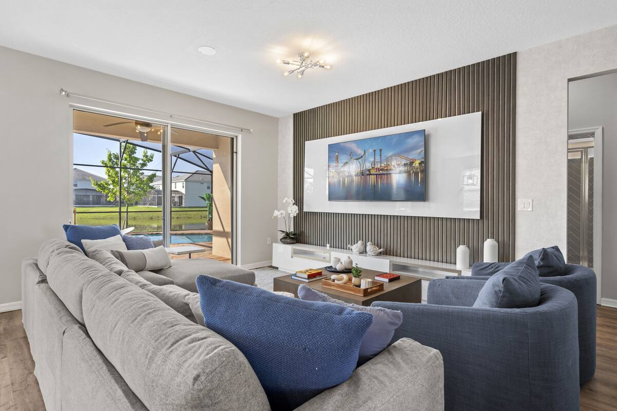 A modern living room with a large TV, grey sofas, and a coffee table with decorative items.