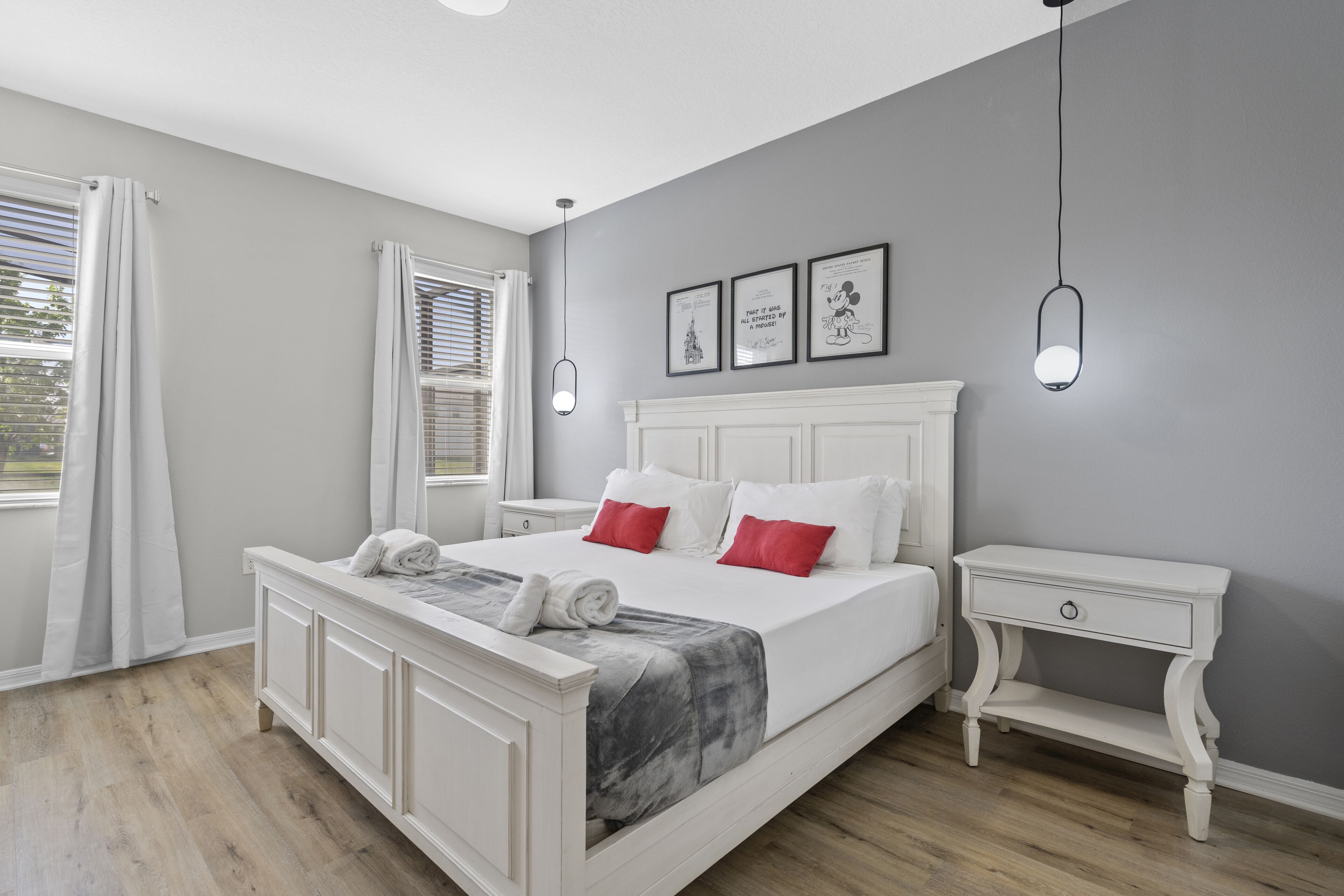 Une chambre à coucher comprenant un lit, des tables de chevet, une commode et une fenêtre avec des rideaux.