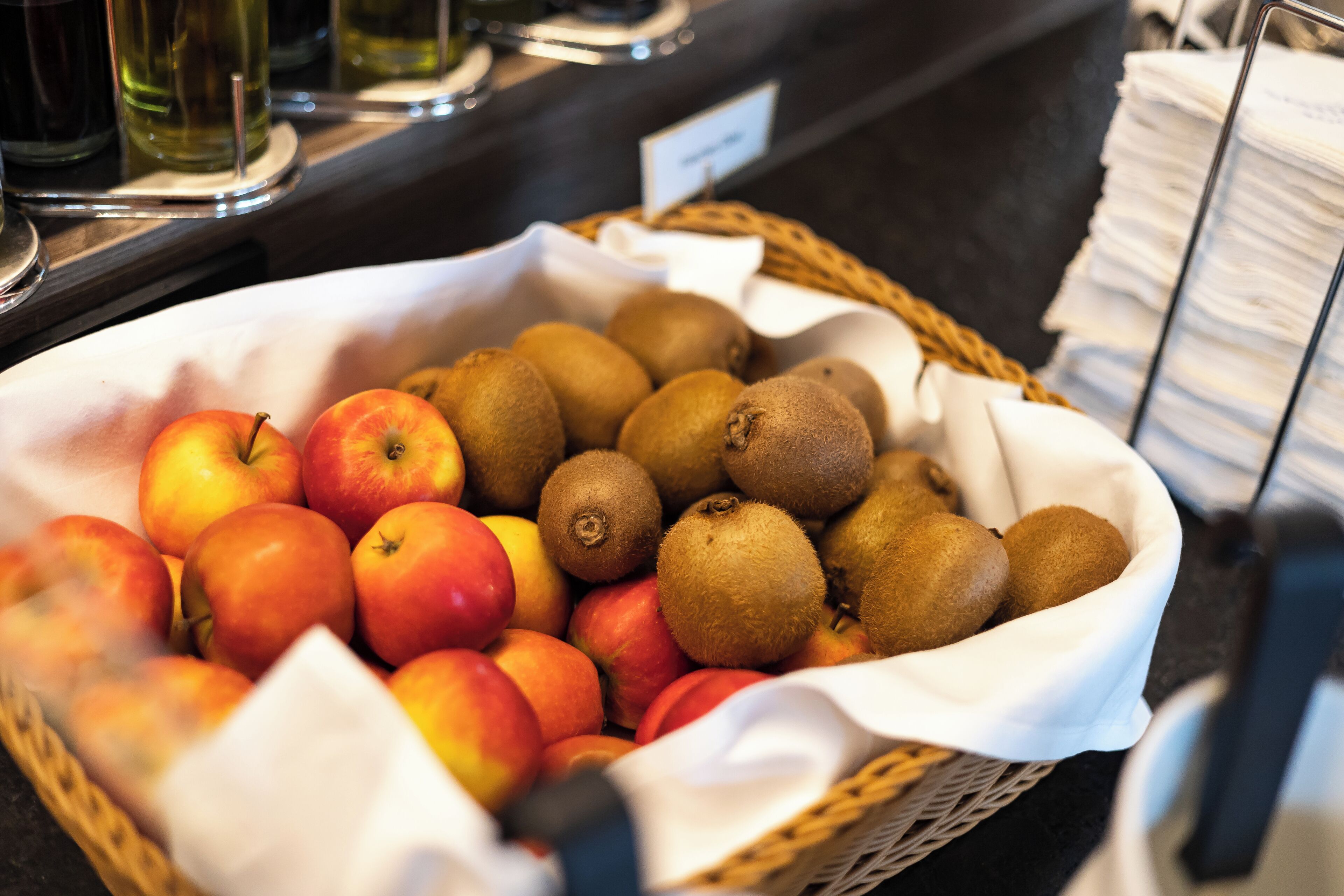 Una cesta de manzanas y kiwis sobre una encimera.