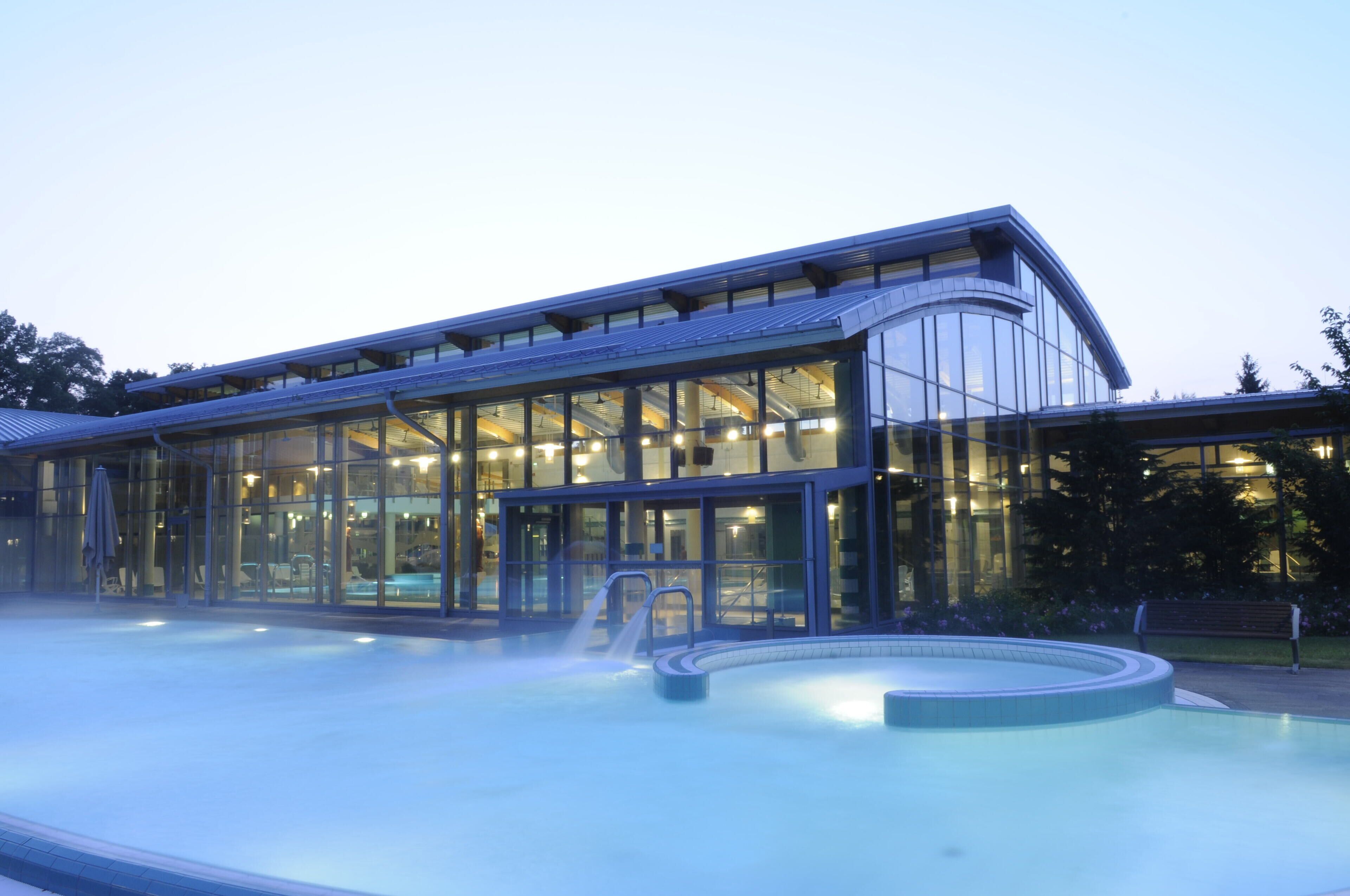 Un edificio moderno con amplios ventanales y una zona de piscina con fuente.