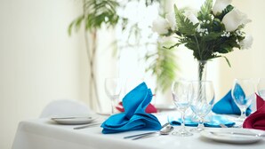 Ein Esstisch ist gedeckt, mit einer Vase weißer Blumen und blauen Servietten.