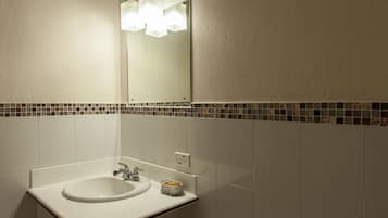 A bathroom with a white sink, a mirror, and a tiled backsplash.