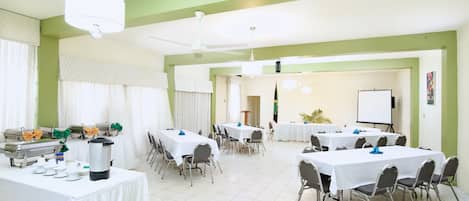 A conference room with multiple tables and chairs, a whiteboard, and a projector screen.