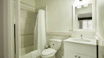 A bathroom with a shower, toilet, sink, and a window with a view.