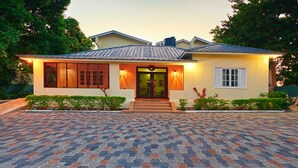 Ein zweigeschossiges Haus mit einem bepflasterten Auffahrt, einem Hauseingang mit Treppe und einem kleinen Garten.