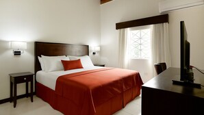 Ein Hotelzimmer mit Bett, Nachttischen, einem Schreibtisch und einer Klimaanlage.