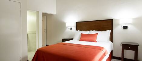 A hotel room with a bed, a nightstand, a wardrobe, and a door.