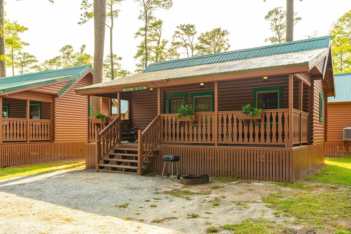 A wooden cabin with a porch, a staircase, and a sign that reads "Welcome to X-14".
